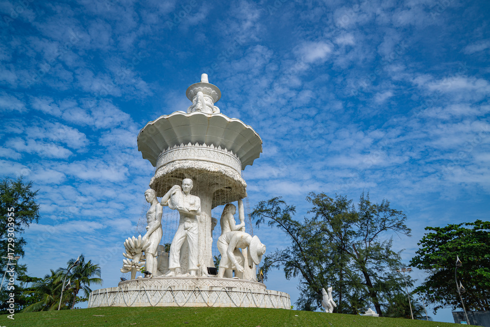 Obraz premium Phuket Thailand.13 August 2025: The sculpture at the Karon Beach roundabout stands beneath a sky filled with small, fluffy clouds, gently diffusing the sunlight and casting a soft light over the scene
