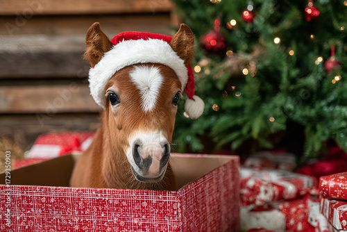 A foal wearing a Santa hat. Against the backdrop of a Christmas tree.