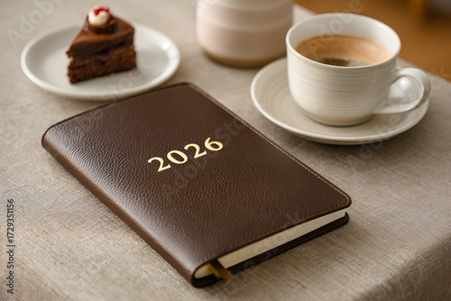 A diary planner for 2026, on a table with coffee and dessert.