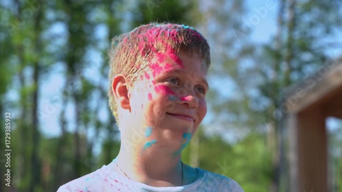 Happy teenage boy with colorful holi powder on his face