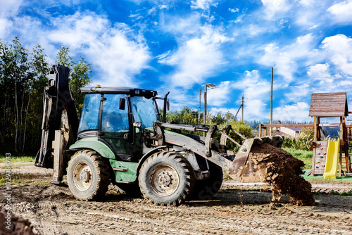 Loader with bucket filled with sand moves on dirt road track, working on construction task.