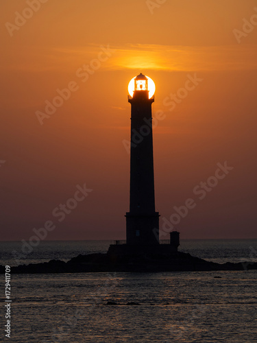 Faro marítimo con el sol poniéndose detras iluminando la bombilla en el Port de Goury, Normandia Francia, viajando en verano de 2022