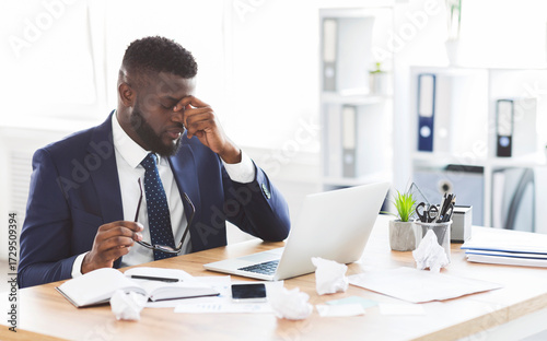 Problems at job. Upset african american businessman massaging his nose bridge holding glasses in hand, copy space