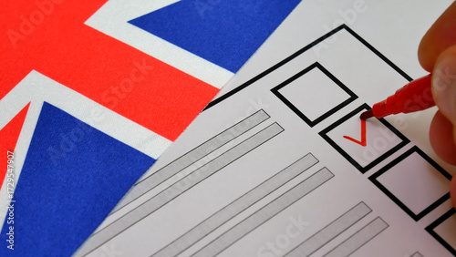 Red marker makes check next to candidate name on ballot. UK elections. Union Jack in background. Voter exercises right to vote in free, fair election process, shaping future through democracy