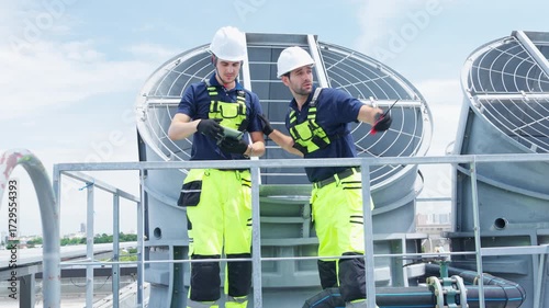 Industrial engineer teamwork working maintenance building exterior cooling systems. Male technician worker in safety uniform working and inspect pipeline valves air HVAC systems at construction site
