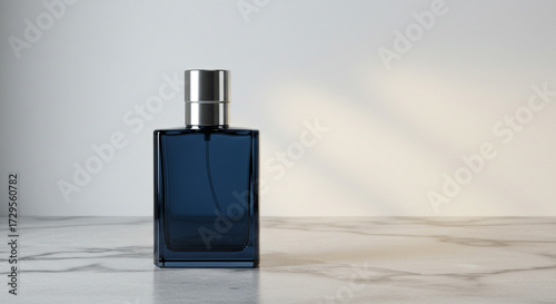 Elegant dark blue glass perfume bottle with silver cap rests on a polished marble surface, suggesting luxury and sophistication.