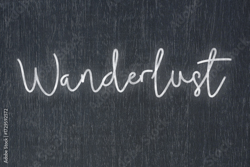 A blackboard with a handwritten chalk message that says wanderlust, a powerful symbol of business success and motivation in educational and production concepts.
