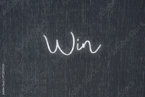 A blackboard with a handwritten chalk message that says win, a powerful symbol of business success and motivation in educational and production concepts.