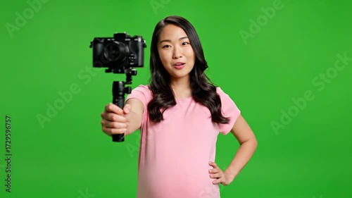 Pregnant Asian Vlogger Recording Video with Camera on Green Screen.