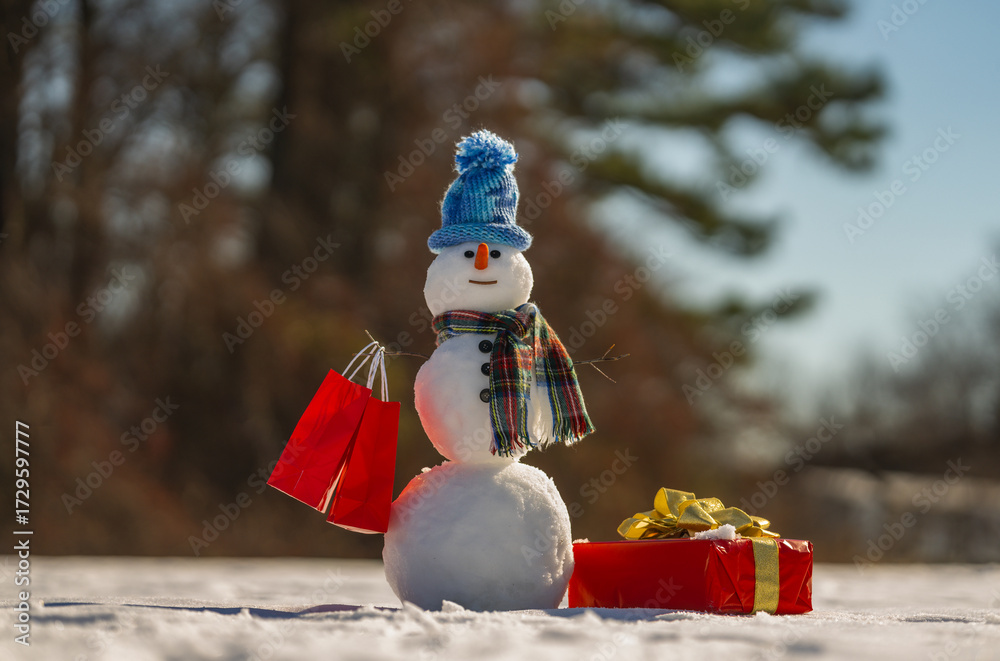 Obraz premium Winter theme. Snowman holding gift. Christmas snowman with festive package. Winter presents with snowmen. Snowman with gift boxes. Greeting card for winter. New Year gifts. Winter banner.