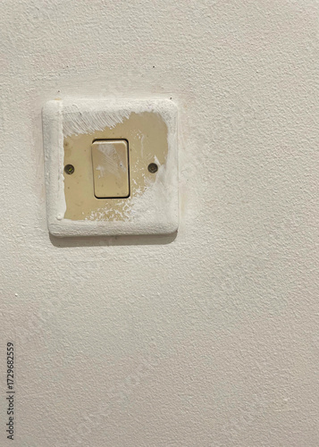 Old single light switch on painted white wall background, vintage electrical power button for home interior design