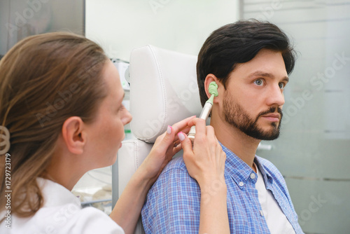 Audiologist creating an personal earplugs or custom molded hearing aid in a clinic. Professional using impression material for precise patient fitting of custom ear plug.