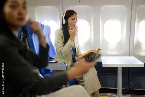 Foto Young woman yawning, feeling tired on airplane flight