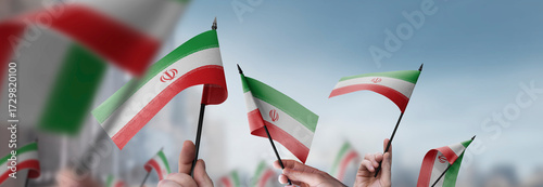 Foto Iran flags in their hands on a blurred urban background