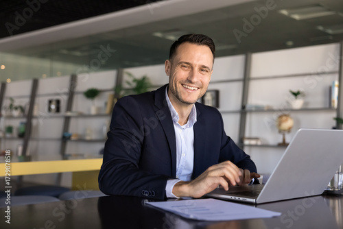 Fotografia Businessman sit at desk in contemporary office with laptop