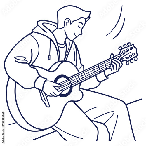 A young man wearing a hoodie sits comfortably and plays an acoustic guitar with his eyes closed in a relaxed and joyful manner enjoying the music he creates