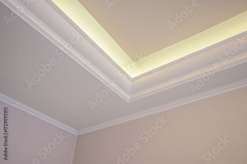 Elegant ceiling corner featuring white crown molding and indirect lighting.  Clean lines & soft glow