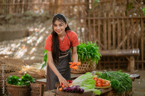 Obraz na plátne A young woman proudly showcases a variety of fresh, vibrant vegetables in a live