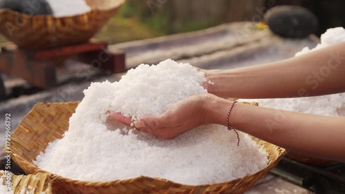 Farmer hands with natural bali sea salt, pure and coarse, hand harvested, woven bamboo basket, slow motion