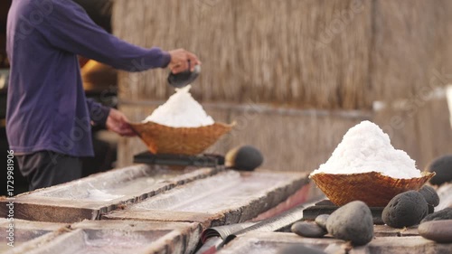 Traditional sea salt production in bali, farmer harvesting natural crystalized salt from coconut trunk, farming, slow motion