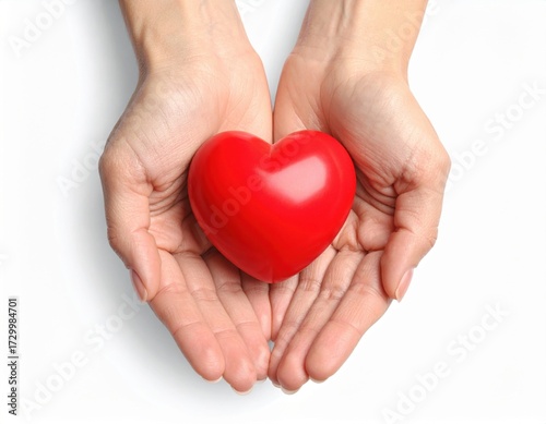 Cupped hands gently present a vibrant red heart symbol against a crisp white studio background, conveying messages of love, care, and health.