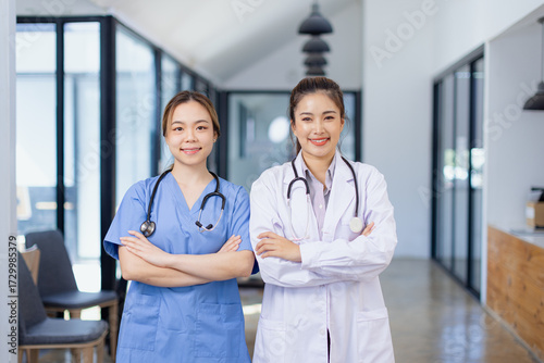 Two medicine doctor woman in white coat stands arms crossed in modern medical clinic, Medical and Healthcare concept.