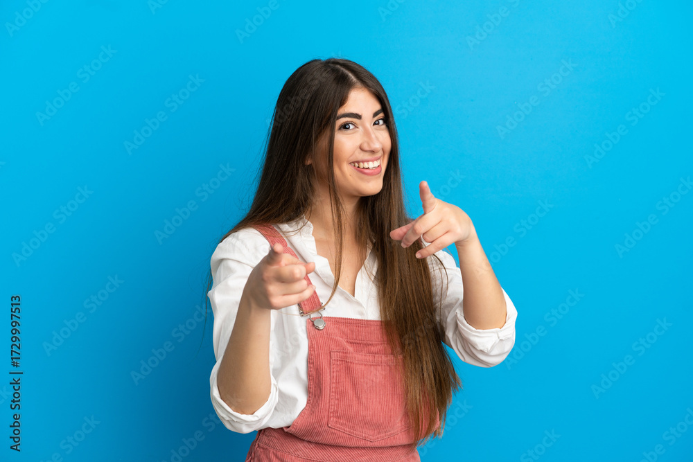 Fototapeta premium Young caucasian woman isolated on blue background surprised and pointing front