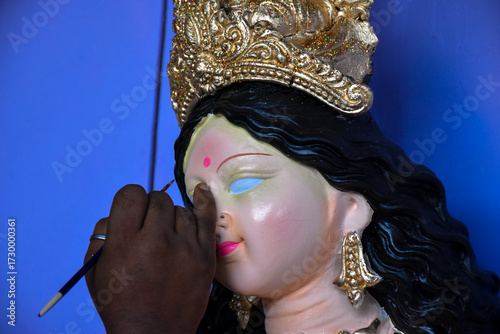 An artiest has been drawing and painting eyes of goddess Durga. Clay idol of Hindu goddess Durga is under preparation.