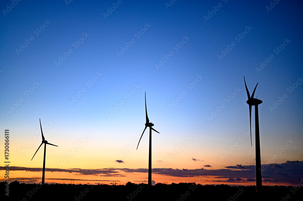 Obraz premium Beautiful colourful sunset silhouettes of wind turbines, windmill, copy space.