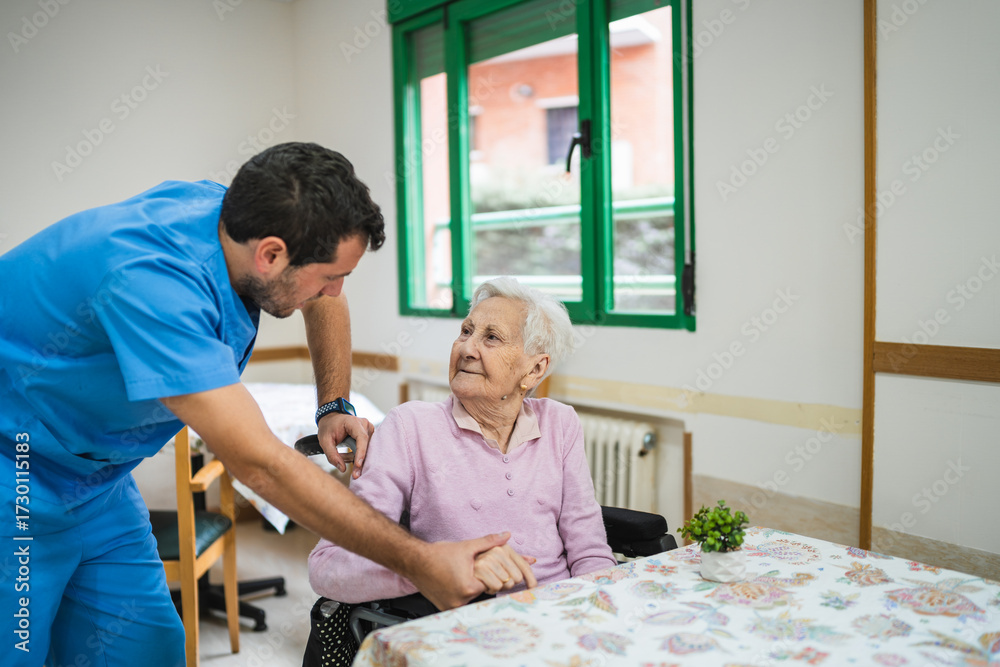 Obraz premium Professional caregiver helping an elderly woman in a wheelchair, providing support and comfort in a caring nursing home environment