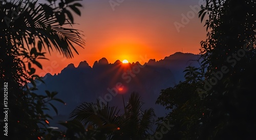 Breathtaking sunset illuminates jagged mountain peaks framed by lush tropical foliage creating a serene and vibrant natural landscape at golden hour