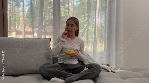 Teenage girl. Enjoying a bowl of crunchy potato chips while relaxing at home in the afternoon sun.
