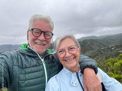 Portrait of happy elderly couple embrace  on a mountain excursion in La Gomera island expressing happiness and freedom. Senior man and woman looking at camera smiling
