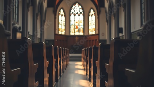 A serene church interior illuminated by stained glass, with empty wooden pews in focus.