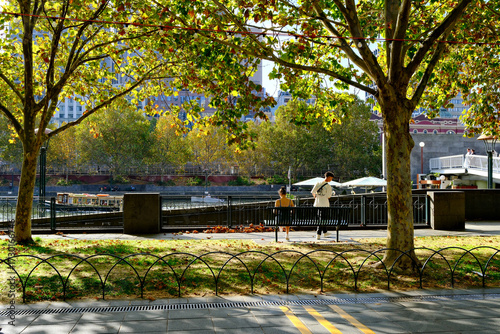 Photos Shaded trees and a couple sitting on a bench along the Yarra River in Melbourne CBD, Australia, offering a peaceful green space in the city center