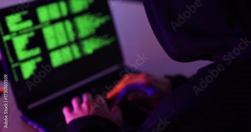 Shot of the back hooded hacker  try to break through the security  with coding on the screen
