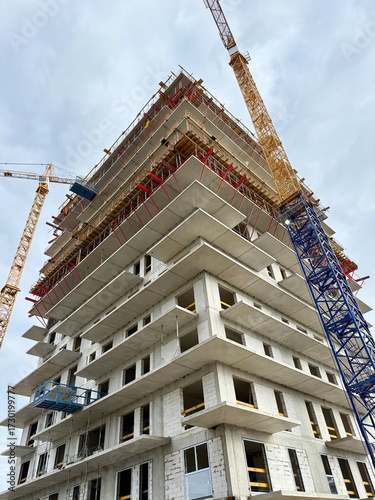 High-rise skyscraper under construction with cranes and scaffolding. Modern urban development in progress.