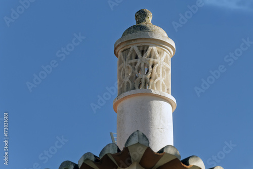 Fototapeta Ornate chimney with decorative top structure Terracotta roof tiles below in Port