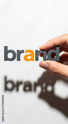 Hand holding gray and orange letters spelling 