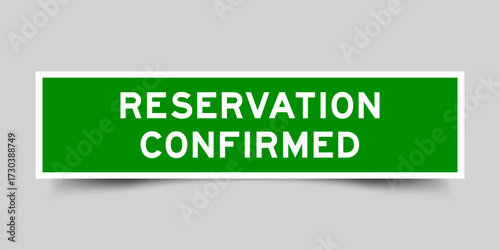 Green color square shape sticker label with word reservation confirmed on gray background