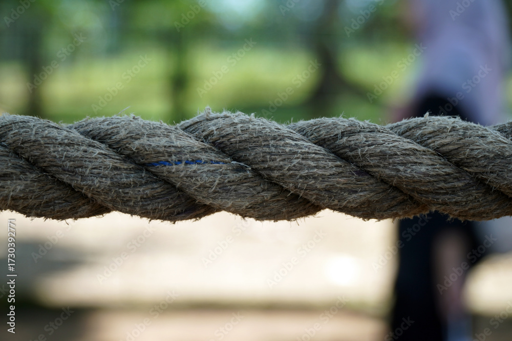 Fototapeta premium A close-up view of a strong, thick rope with a visible braided texture. The image represents strength, connection, and a rustic, natural feel.