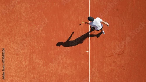 Tennis player practices on clay court, showcasing dynamic movement and skill development. Overhead drone footage highlights focused training, dedication, and precision in sports education.