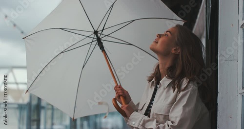 Beautiful young woman outdoors opening umbrella and smiling
