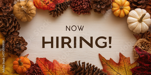 autumn hiring announcement framed by festive border of pinecones, pumpkins and colorful leaves on light wooden background with bold centered text in warm seasonal composition