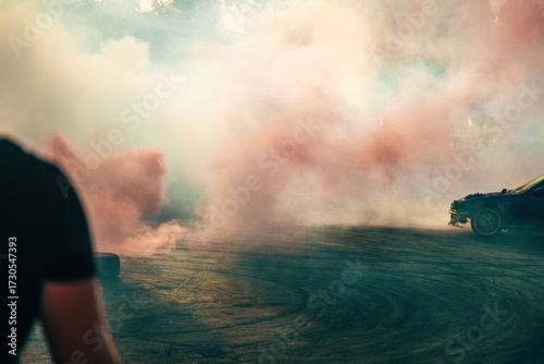 Car drifting on asphalt track surrounded by colorful smoke during motorsport show.