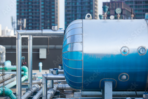 Close-up of industrial pressure tanks and piping system on a building rooftop, representing HVAC infrastructure, energy management, and mechanical engineering in urban facilities.