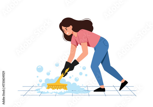 Brunette woman scrubs tiled floor with yellow brush wearing gloves and jeans