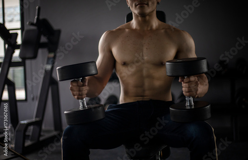 Athletic shirtless handsome young man, muscular young men are exercising with weights in a gym.
