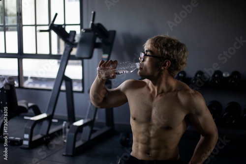 Athletic shirtless handsome young man, muscular young men are exercising with weights in a gym.
