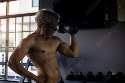Athletic shirtless handsome young man, muscular young men are exercising with weights in a gym.
